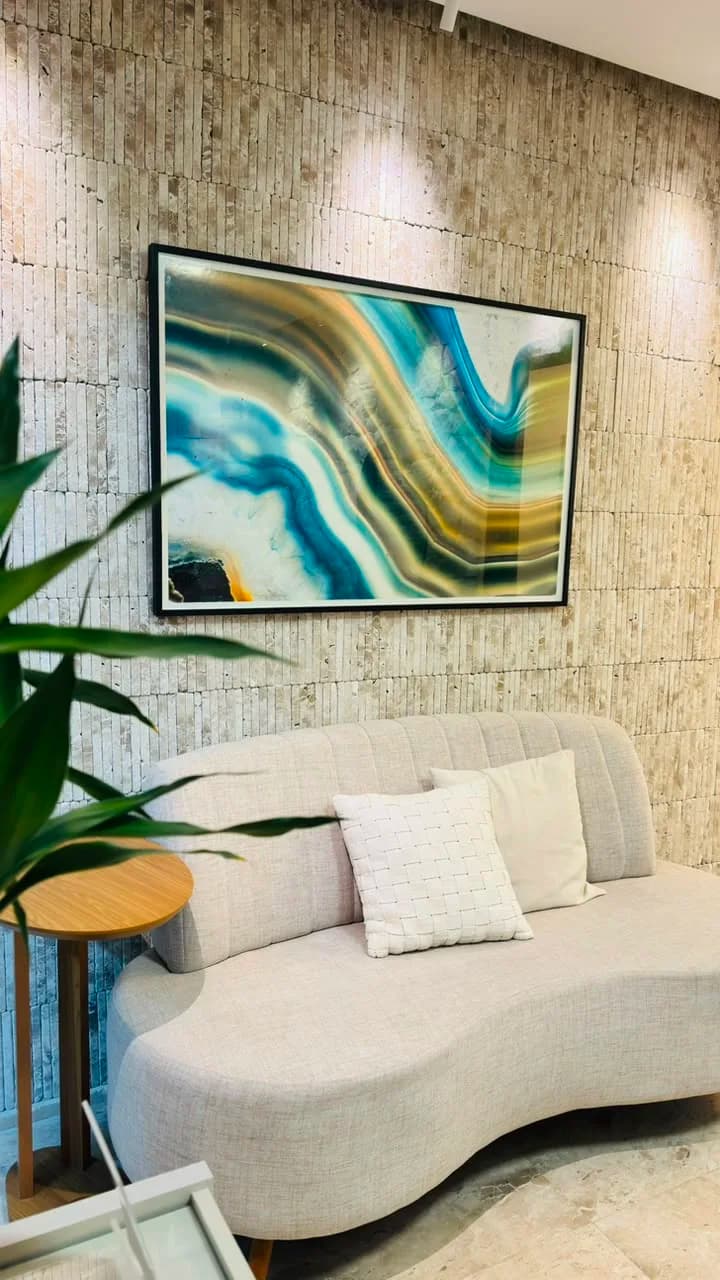 Sofá curvo bege com quadro de ágata e parede de pedra